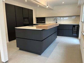 A modern kitchen with a central island, black cabinetry, and a white countertop. - mit Pool by Interhome (Nürtingen)