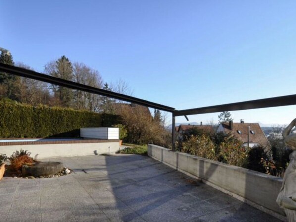 A rooftop terrace with a view of houses and trees.
