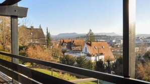 Un balcon avec vue sur la ville et les montagnes.