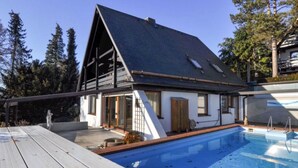 Une maison moderne dotée d’une piscine, de grandes fenêtres et d’une terrasse.