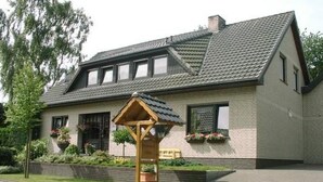 A two-story house with a sloped roof, a wooden porch, and flower boxes on the windowsills. - Wohnung in Börgerwald mit Sauna by Interhome (Surwold)