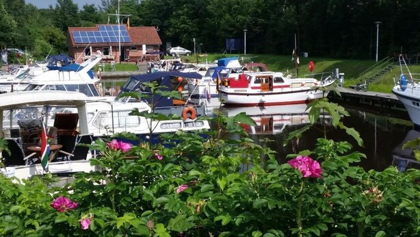 A marina with boats docked, a building with solar panels, and lush greenery. - Wohnung in Börgerwald mit Sauna by Interhome (Surwold)