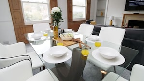A modern dining area with a glass table set for six, surrounded by white chairs. - 3-Schlafzimmer-Wohnung im georgianischen Stil - beste Lage - 7 Gäste by Interhome (Bath)