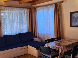 A cozy room with a sofa, a dining table, and curtains.