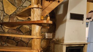 En spiraltrappa i trä med en bakgrund av en vägg i sten och en vedeldad kamin nedanför.