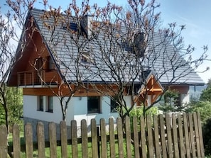 A modern two-story house with a sloped roof, wooden exterior, and a visible chimney.