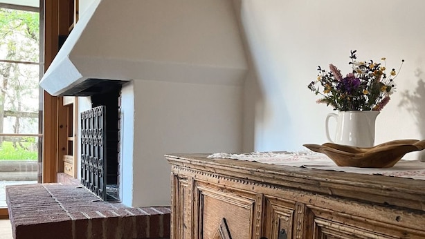 A wooden cabinet with a decorative handle, a white pitcher with flowers, and a brick bench in a room with wooden flooring and a sloped ceiling. - Curtin Duas by Interhome (Fex / Fextal (Sils im Engadin)