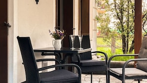An outdoor patio with a table and four chairs, a vase with flowers, and a view of greenery and buildings in the background. - Curtin Duas by Interhome (Fex / Fextal (Sils im Engadin)