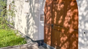 A building with a large wooden door, a stone pathway, and a small garden area. - Curtin Duas by Interhome (Fex / Fextal (Sils im Engadin)