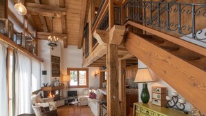 A cozy cabin interior with a wooden staircase, a dining area with a table set for four, and a living room with a sofa and a fireplace. - Chesa Cavril by Interhome (Maloja)