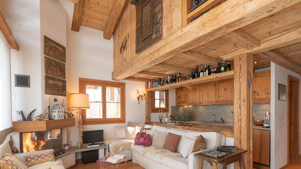 A cozy living room with a fireplace, wooden beams, and a sofa. - Chesa Cavril by Interhome (Maloja)