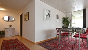 Een eethoek met een tafel, stoelen, een spiegel en lijstwerken aan de muur.