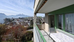 Een balkon met een tafel en stoelen, met uitzicht op een stad en een berg op de achtergrond.