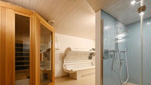Een moderne badkamer met een houten kast, een sauna en een douchecabine met glazen wanden.
