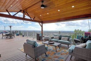 A covered outdoor patio with wicker furniture, a dining table, and a view of the cityscape. - Home in the Sky! Relax in 4br/2ba Home with Amazing Panoramic SD views. (Spring Valley)