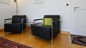 A living room with two black leather chairs, a small table, and a floor lamp. There are two framed artworks on the wall. - Haus Stirnemann/ Wohnung H-2 by Interhome (Weggis)