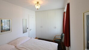 A bedroom with a bed, a wardrobe, a chair, and a ceiling light. - Haus Stirnemann/ Wohnung H-2 by Interhome (Weggis)