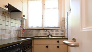 A compact kitchen with a window above the sink, a dishwasher, and a stove. - Haus Stirnemann/ Wohnung H-2 by Interhome (Weggis)