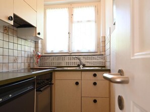 Une cuisine de taille réduite, avec une fenêtre au-dessus de l’évier, un lave-vaisselle et une cuisinière.