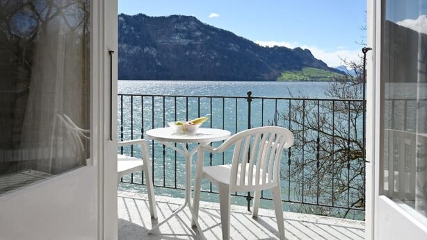 A balcony with a table and chairs, overlooking a lake and mountains. - Haus Stirnemann/ Wohnung H-2 by Interhome (Weggis)