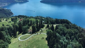 A panoramic view of a lake surrounded by mountains and a small village with a winding road. - Appartement Alpenblick / G6 by Interhome (Weggis)