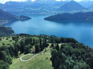A panoramic view of a lake surrounded by mountains, with a winding road and a few buildings visible in the foreground. - Appartement Alpenblick / G6 by Interhome (Weggis)