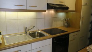 A kitchen with white cabinets, a stainless steel sink, a black dishwasher, and a wooden countertop. - Haus Stirnemann/ Wohnung M-2 by Interhome (Weggis)