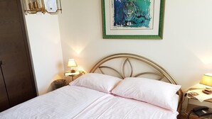A neatly made bed with a headboard, two bedside tables with lamps, a framed picture on the wall, and a wooden door. - Haus Stirnemann/ Wohnung M-2 by Interhome (Weggis)