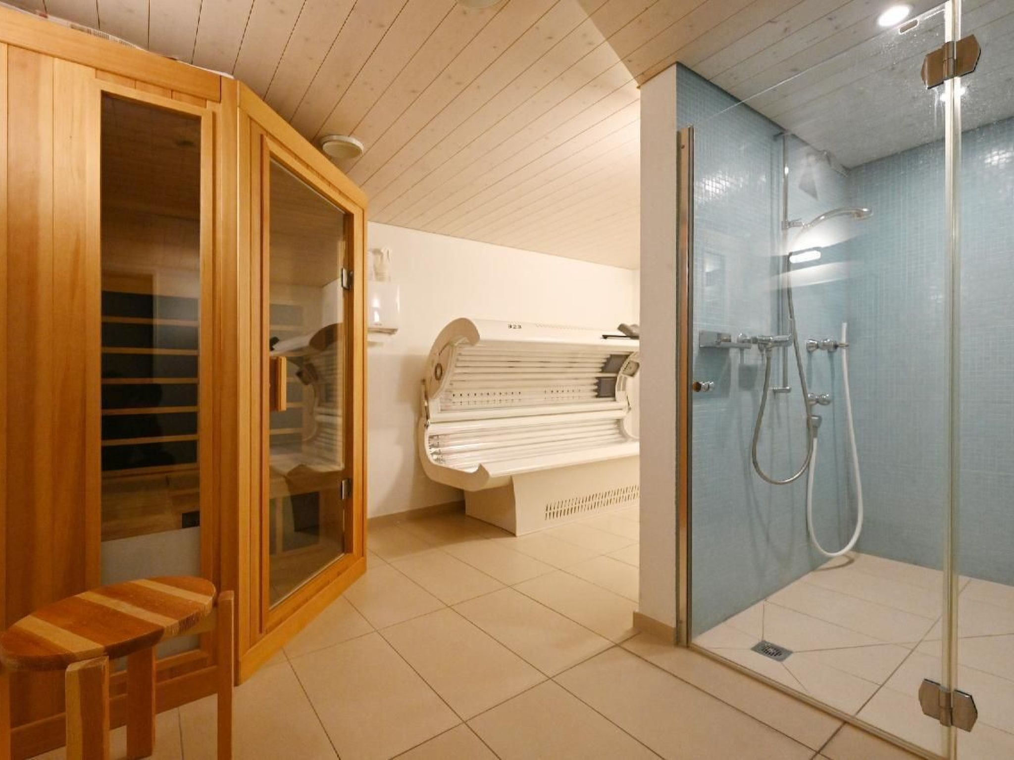 A modern bathroom with a wooden cabinet, a sauna, and a glass-enclosed shower area.