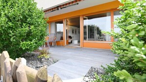 Une maison moderne dotée d’un patio, d’un espace salon extérieur et d’une clôture en bois.