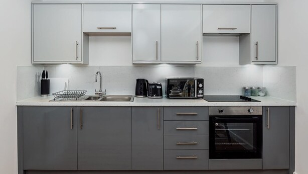 A modern kitchen with grey cabinets, a stainless steel sink, a kettle, a microwave, and an oven. - Brandneue, zentrale 2-Zimmer-Wohnung für 6 Gäste by Interhome (Preston)