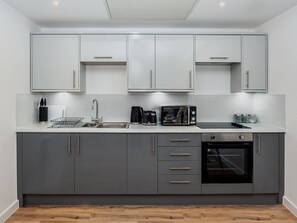 A modern kitchen with grey cabinets, a stainless steel sink, a kettle, a microwave, and an oven. - Brandneue, zentrale 2-Zimmer-Wohnung für 6 Gäste by Interhome (Preston)