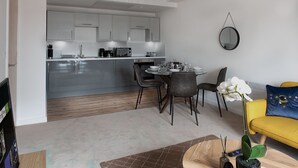 A modern living room with a dining area, a yellow sofa, and a kitchen in the background. - Brandneue, zentrale 2-Zimmer-Wohnung für 6 Gäste by Interhome (Preston)