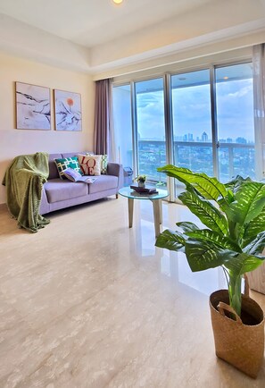 Ein modernes Wohnzimmer mit einer Couch, einem Couchtisch und einem großen Fenster mit Blick auf die Stadt.