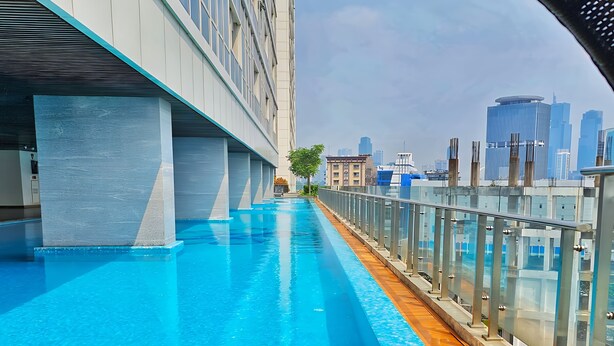 A modern urban pool with a clear view of a city skyline and a bridge in the background. - Manoré By SanLiving - 2BR - Private Lift (Jakarta)