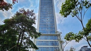 A modern high-rise building with a glass facade, surrounded by greenery and a clear sky. - Manoré By SanLiving - 2BR - Private Lift (Jakarta)
