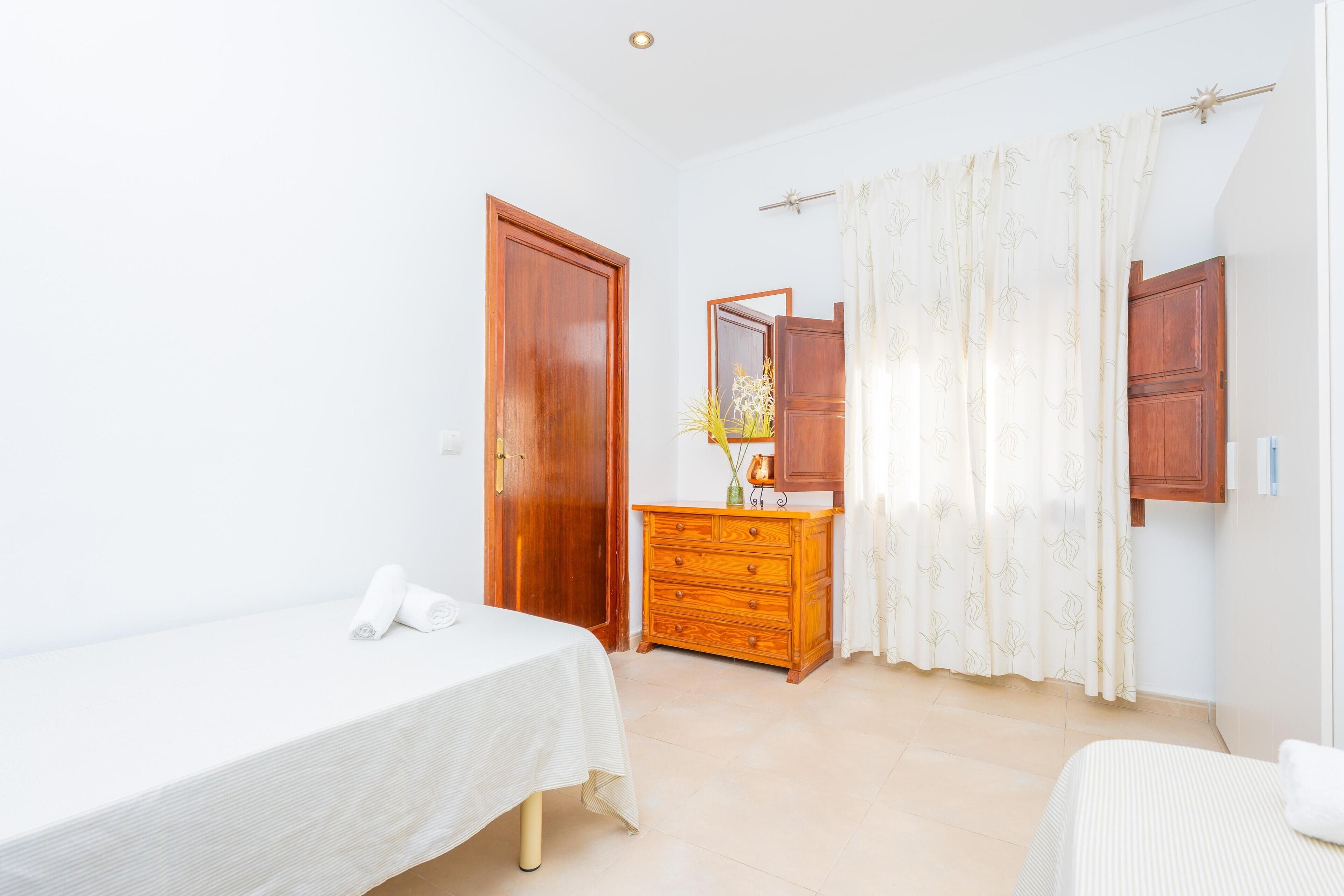 A bedroom with a single bed, a dresser, a mirror, and a door.