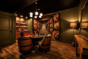 Ein Raum mit einer langen Wand, einer Bar mit Regalen und einem runden Tisch mit Stühlen.