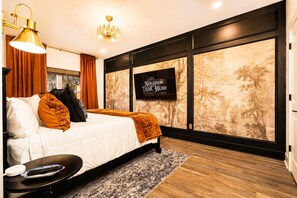 Ein modernes Schlafzimmer mit einem großen Bett, einem Flachbildfernseher und einer Wand mit einem Baumdekor.