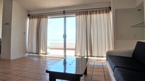 Un salón con un sofá, una mesa de centro y un ventanal corredero que da a un balcón.