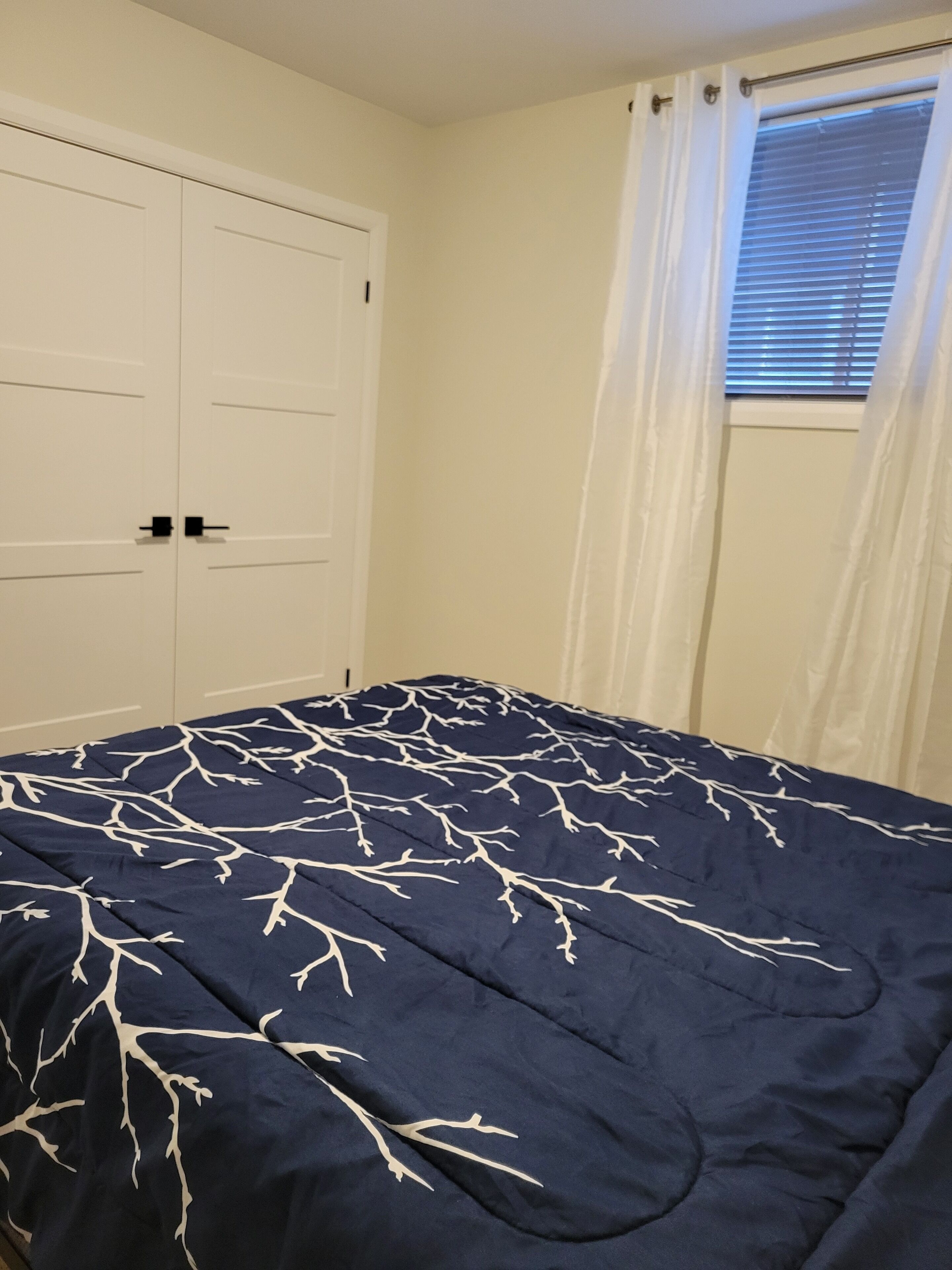 Une chambre à coucher avec un lit, une armoire et une fenêtre avec des rideaux.