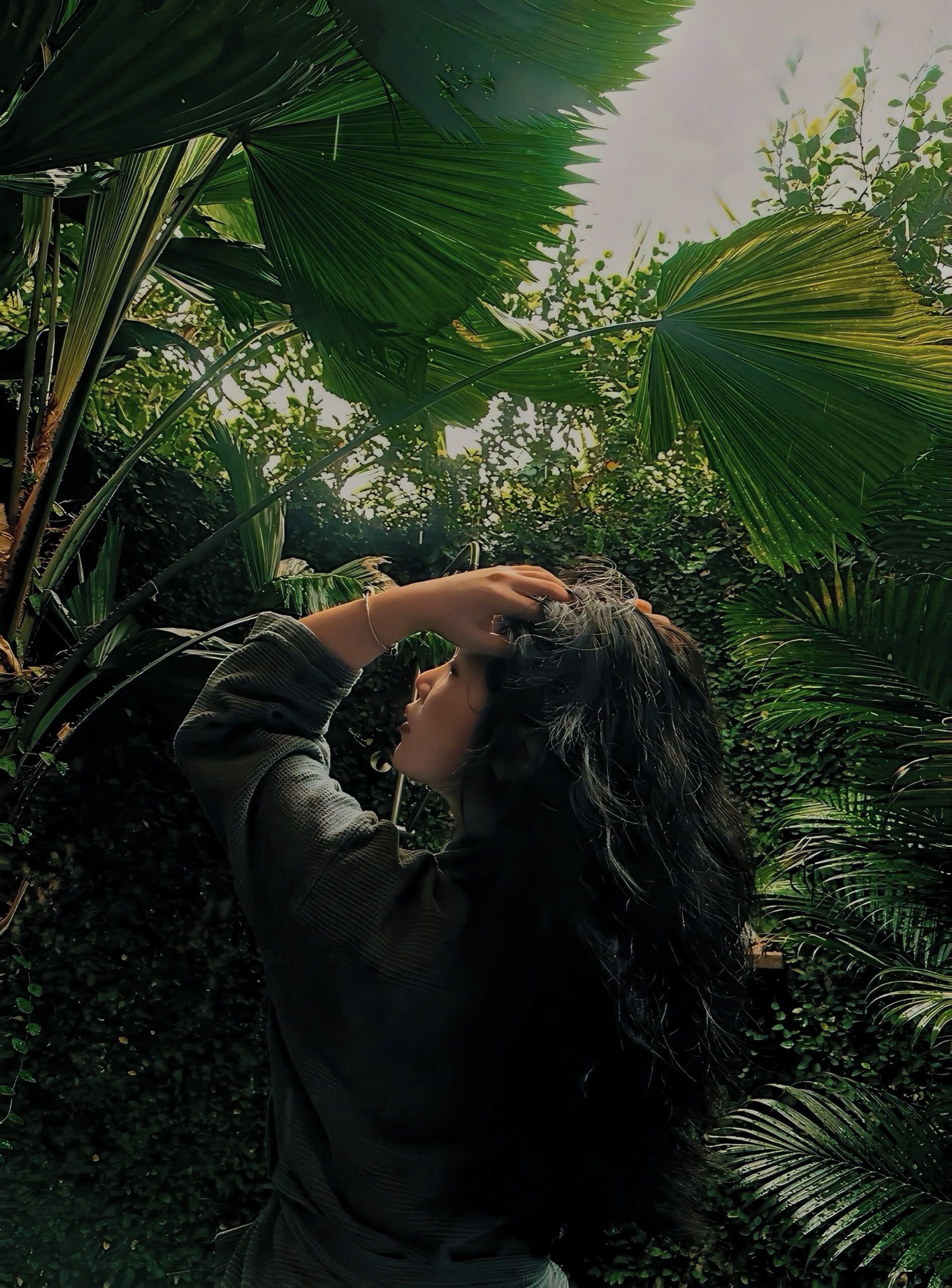 Una persona en un jard ín con follaje denso y diversas plantas.