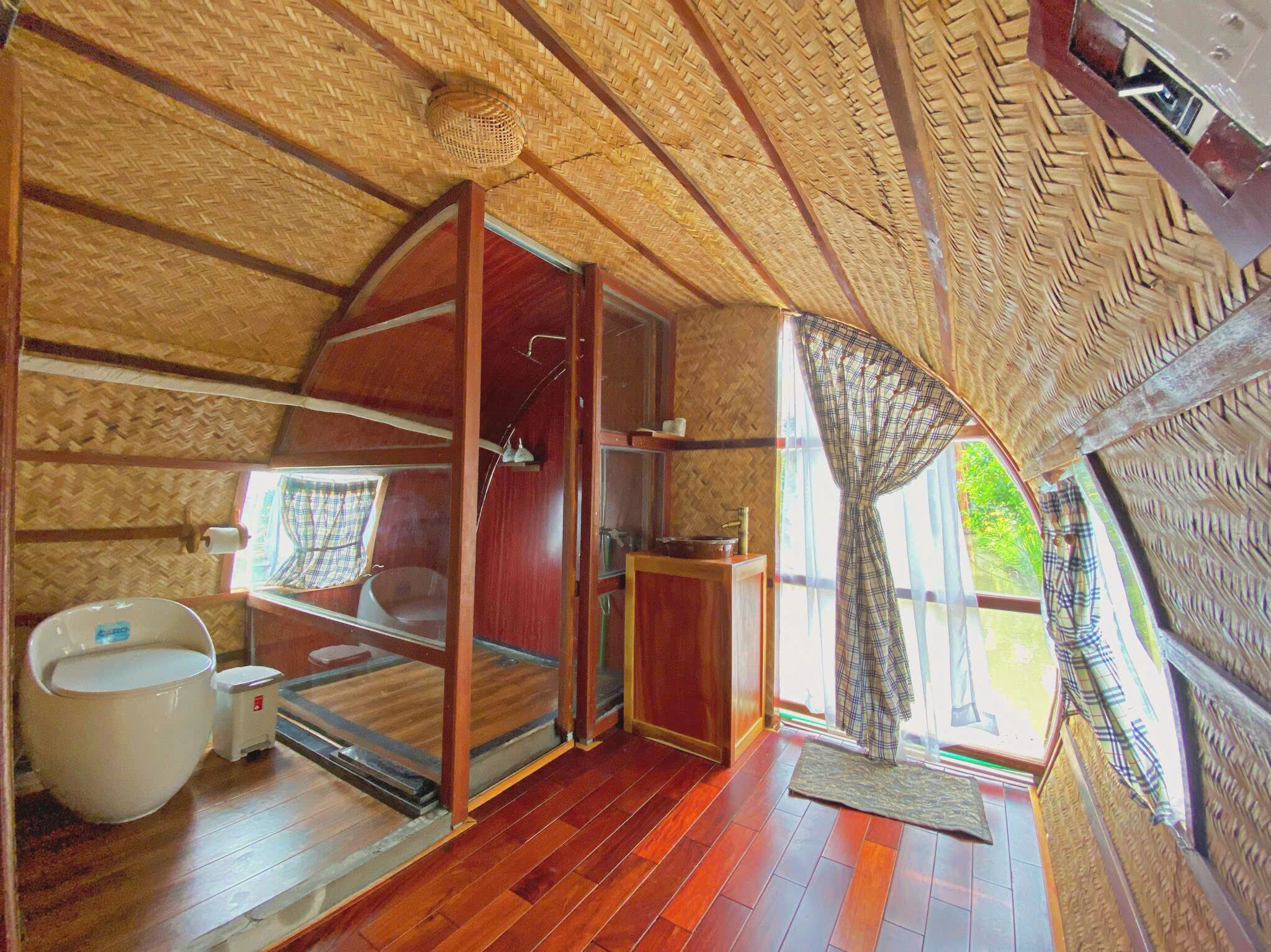 Un intérieur chaleureux, avec des murs en bois, une grande fenêtre, un évier et des toilettes.