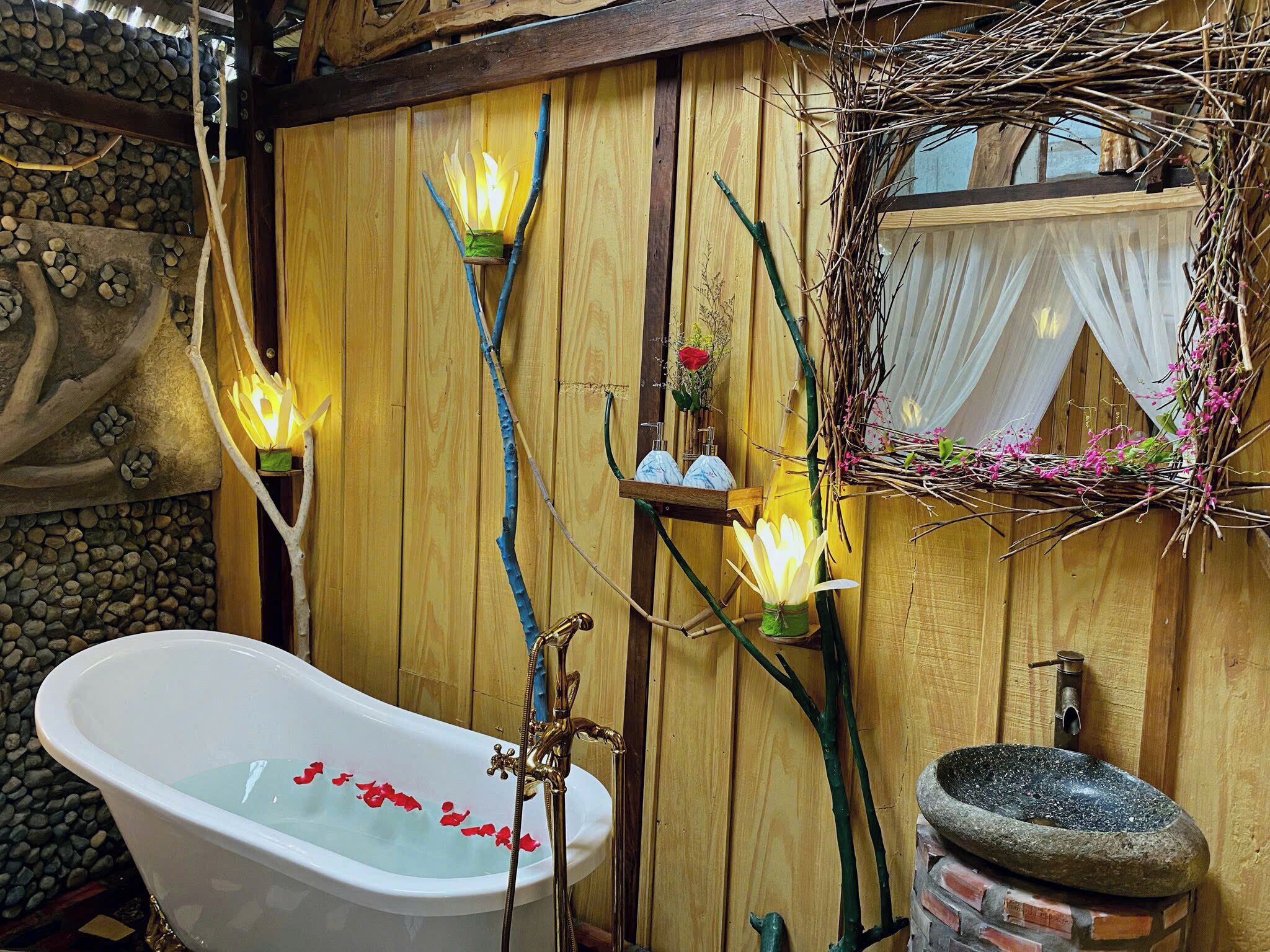 A rustic bathroom with a freestanding bathtub, wooden walls, and decorative branches.