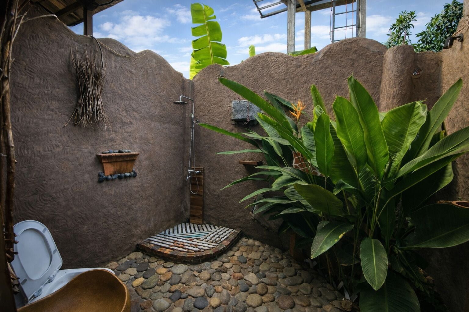 Une salle de bain rustique avec une douche, une petite étagère en bois et des toilettes.