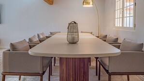 Ein langer Esstisch mit dekorativer Flechtkorb-Mitteldecke, umgeben von Sitzgelegenheiten mit Polstern.