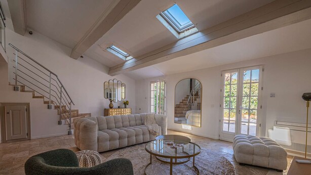 Ein geräumiges Wohnzimmer mit einer großen Couch, einem Couchtisch und einer Treppe, die in eine obere Ebene führt.