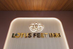 A sign for Lotus Feet Inn with a lotus symbol and the name in gold letters. - Lotus Feet Inn (Varanasi)