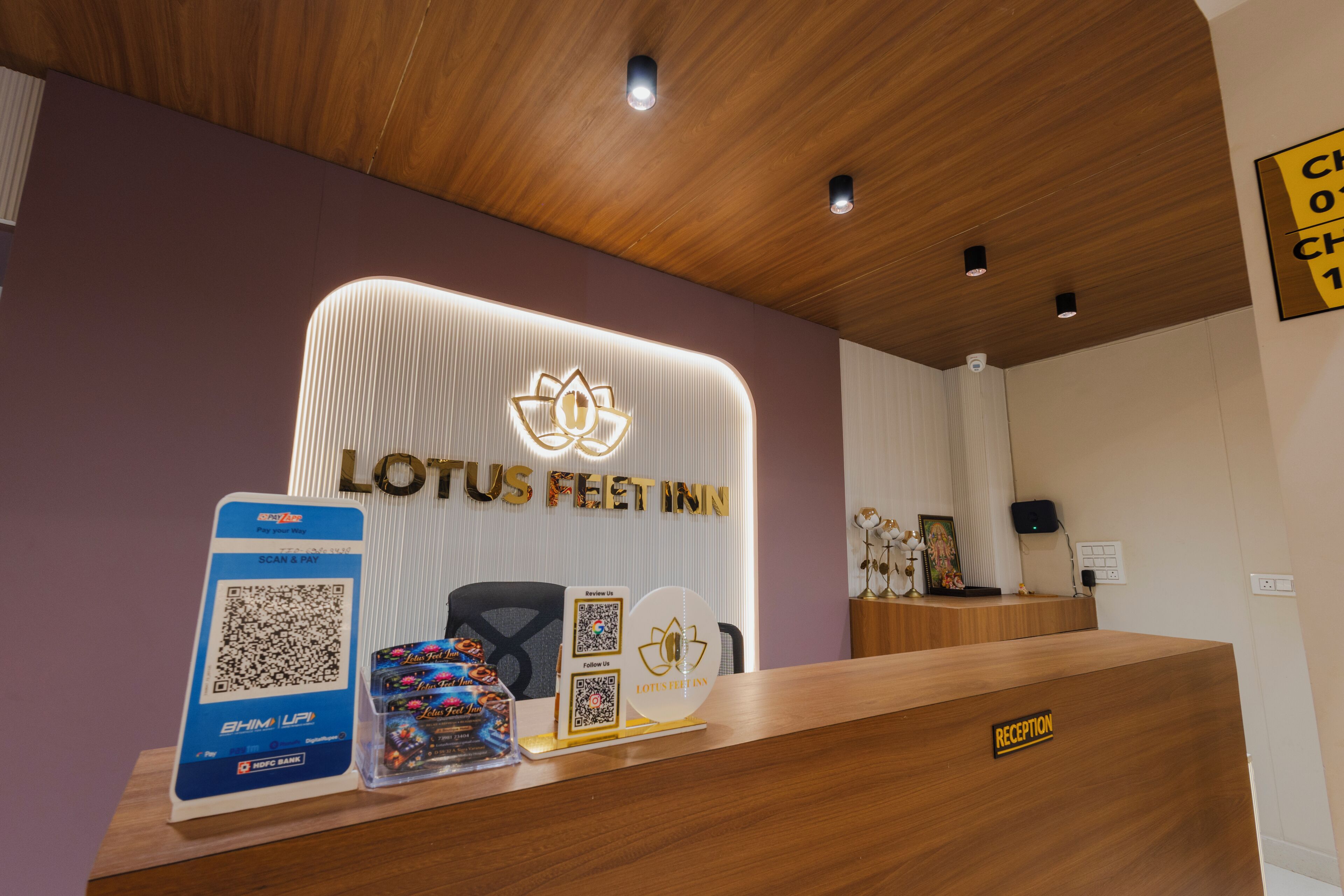 Un comptoir d’accueil avec une enseigne « LOTUS FEET INN », un code QR pour le paiement et une enseigne « RÉCEPTION ».