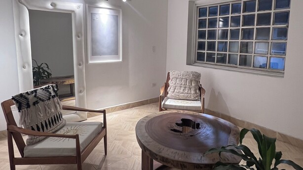 A spacious living room with a large window, a round coffee table, and two wooden chairs. - Room 202 with air conditioning (Cúcuta)